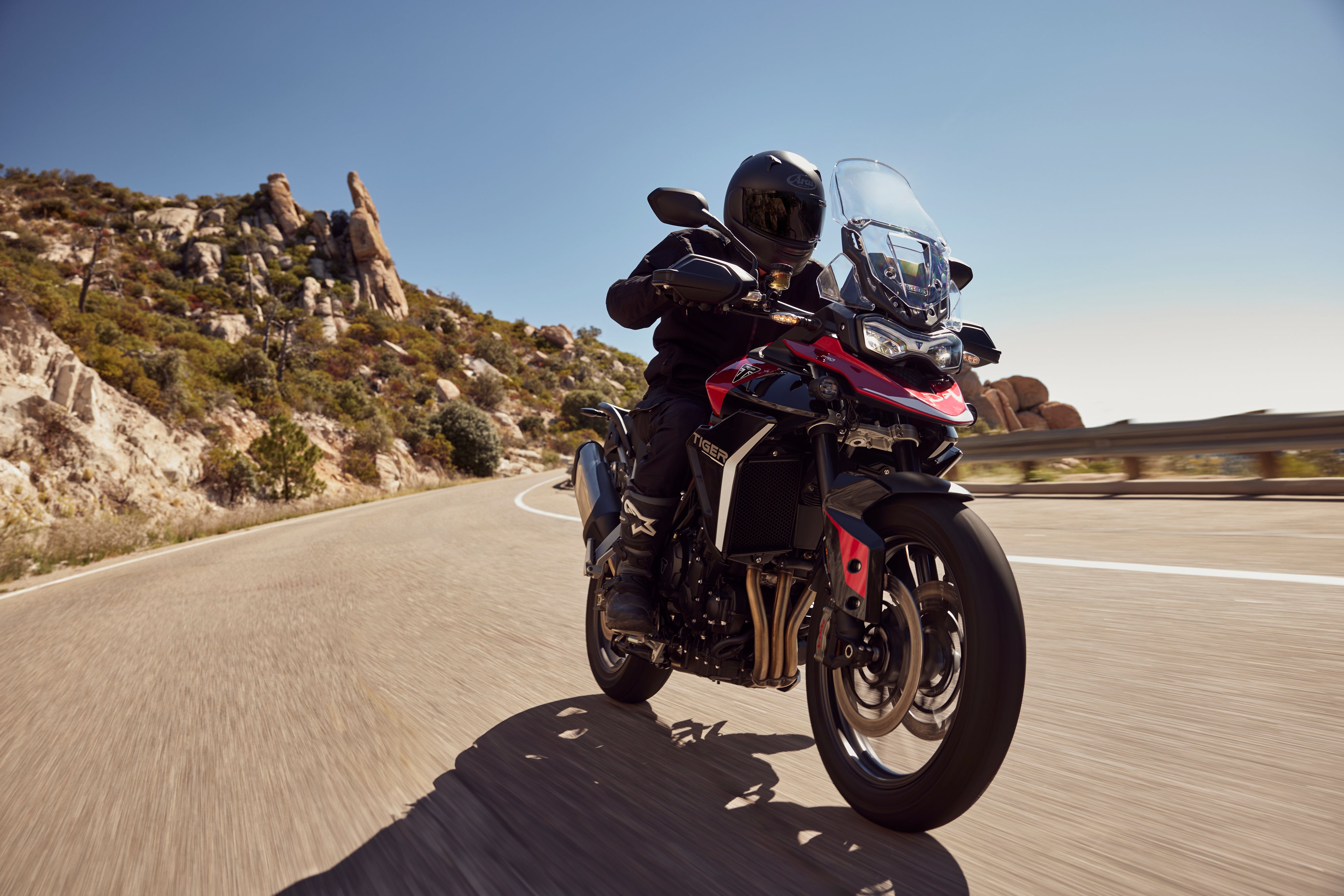 Triumph Tiger 900 GT Pro riding on a winding mountain road, showcasing adventure touring performance and responsive suspension.