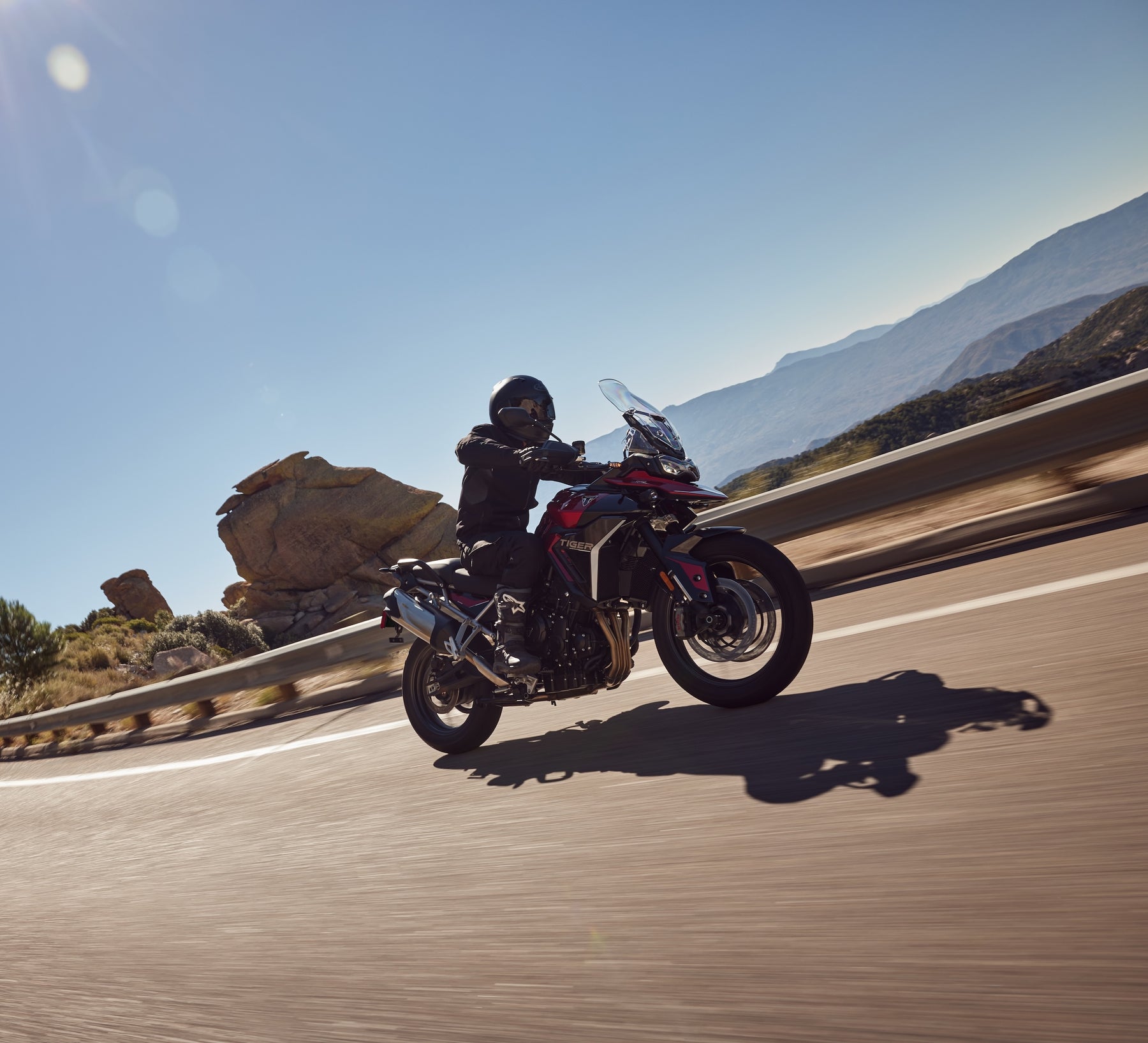 Side view of the Triumph Tiger 900 GT Pro in motion, highlighting the touring windscreen, triple engine, and adventure ergonomics during a road test.