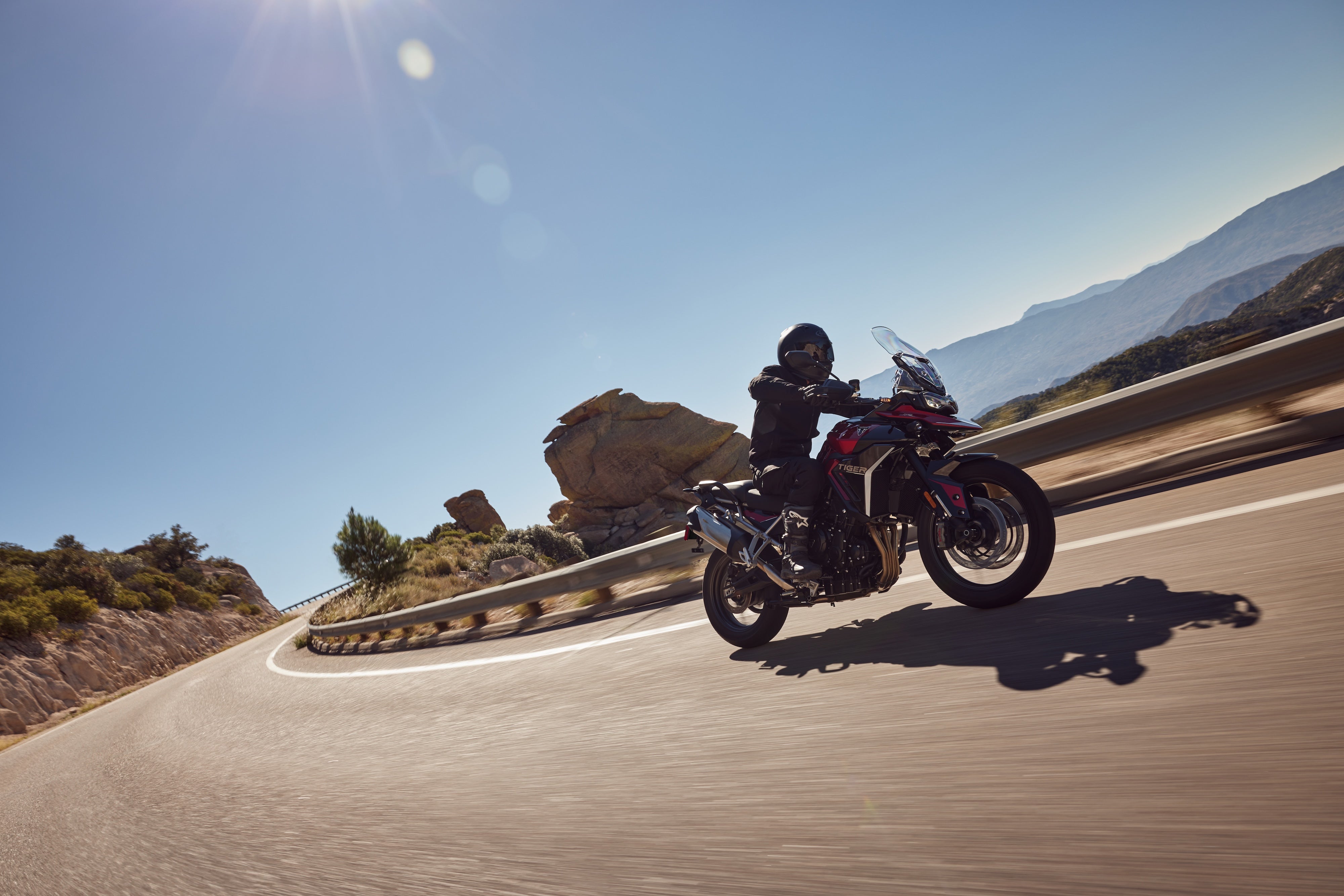 Triumph Tiger 900 GT Pro adventure motorcycle riding on a winding mountain road.