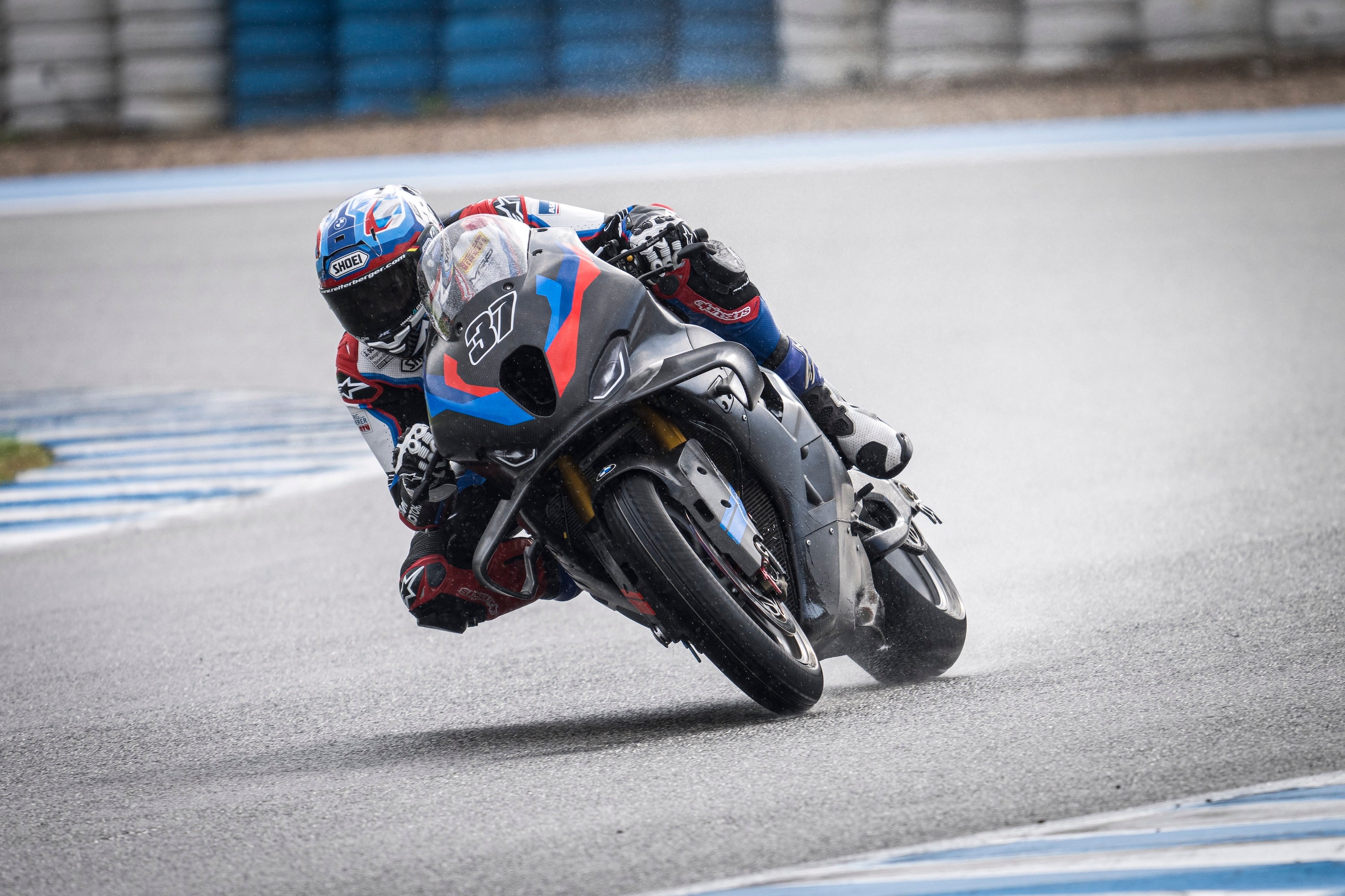 Markus Reiterberger leaning a BMW M 1000 RR into a corner during a rainy 2025 WorldSBK winter test at Circuito de Jerez, Spain.