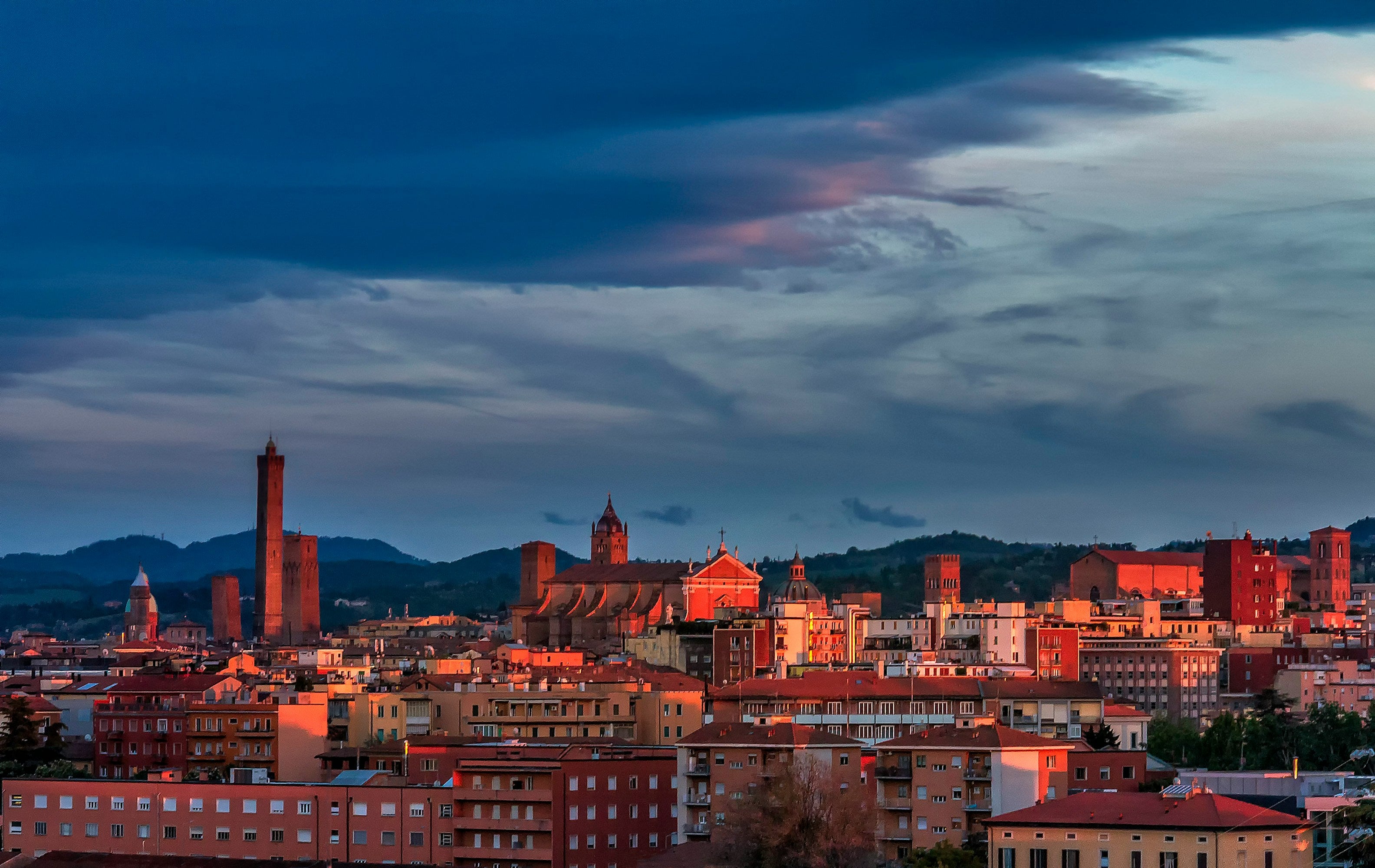 Bologna skyline at sunset with medieval towers and historic city center illuminated in golden light.