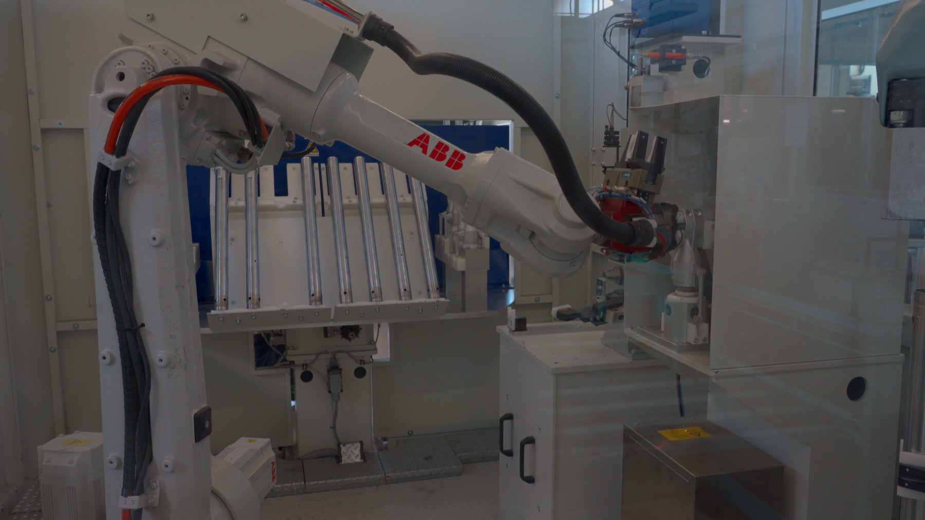 ABB industrial robotic arm operating inside automated testing and manufacturing cell.