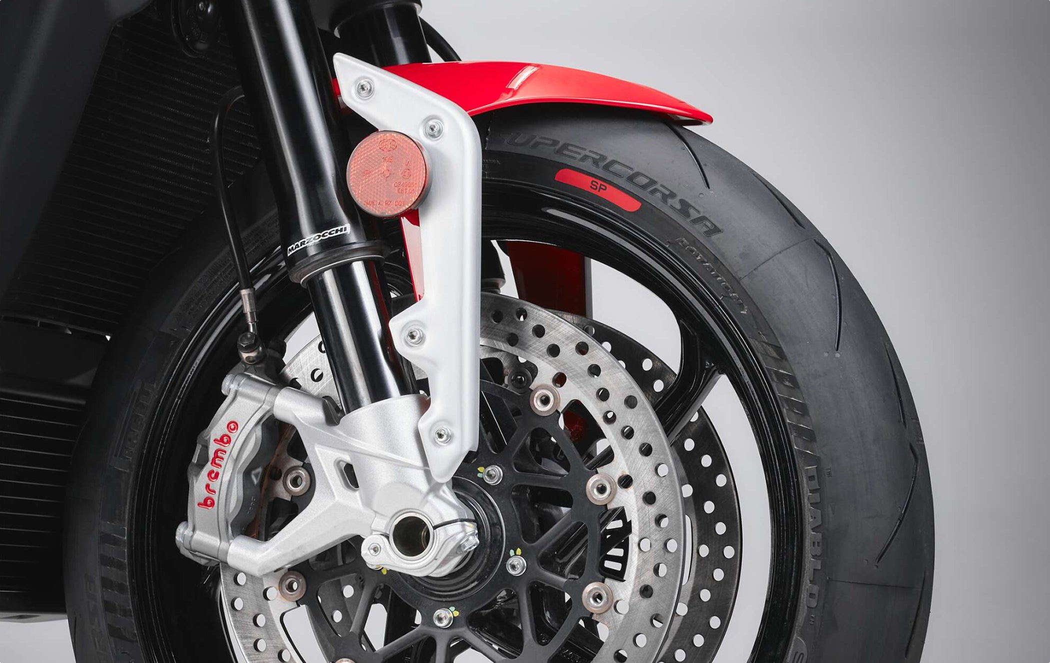 Close-up of Marzocchi motorcycle front fork with Brembo brake caliper and sportbike front wheel assembly.