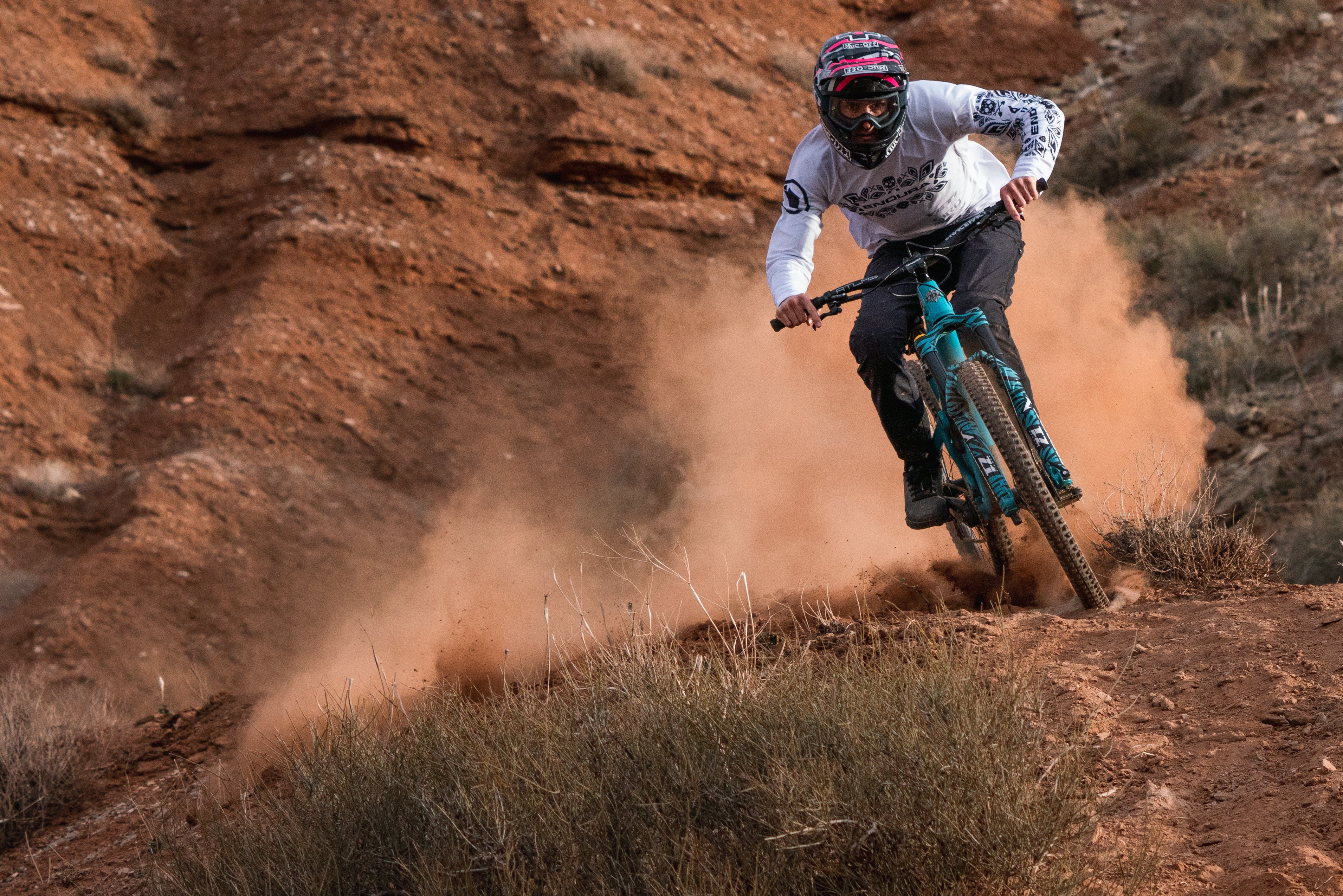 Enduro mountain biker using Marzocchi Z1 forks on a rugged, dusty downhill trail.