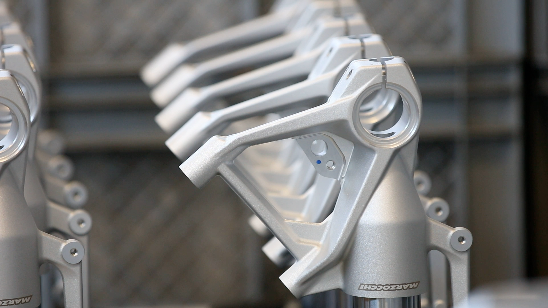Precision-machined motorcycle fork lower castings aligned in production facility.