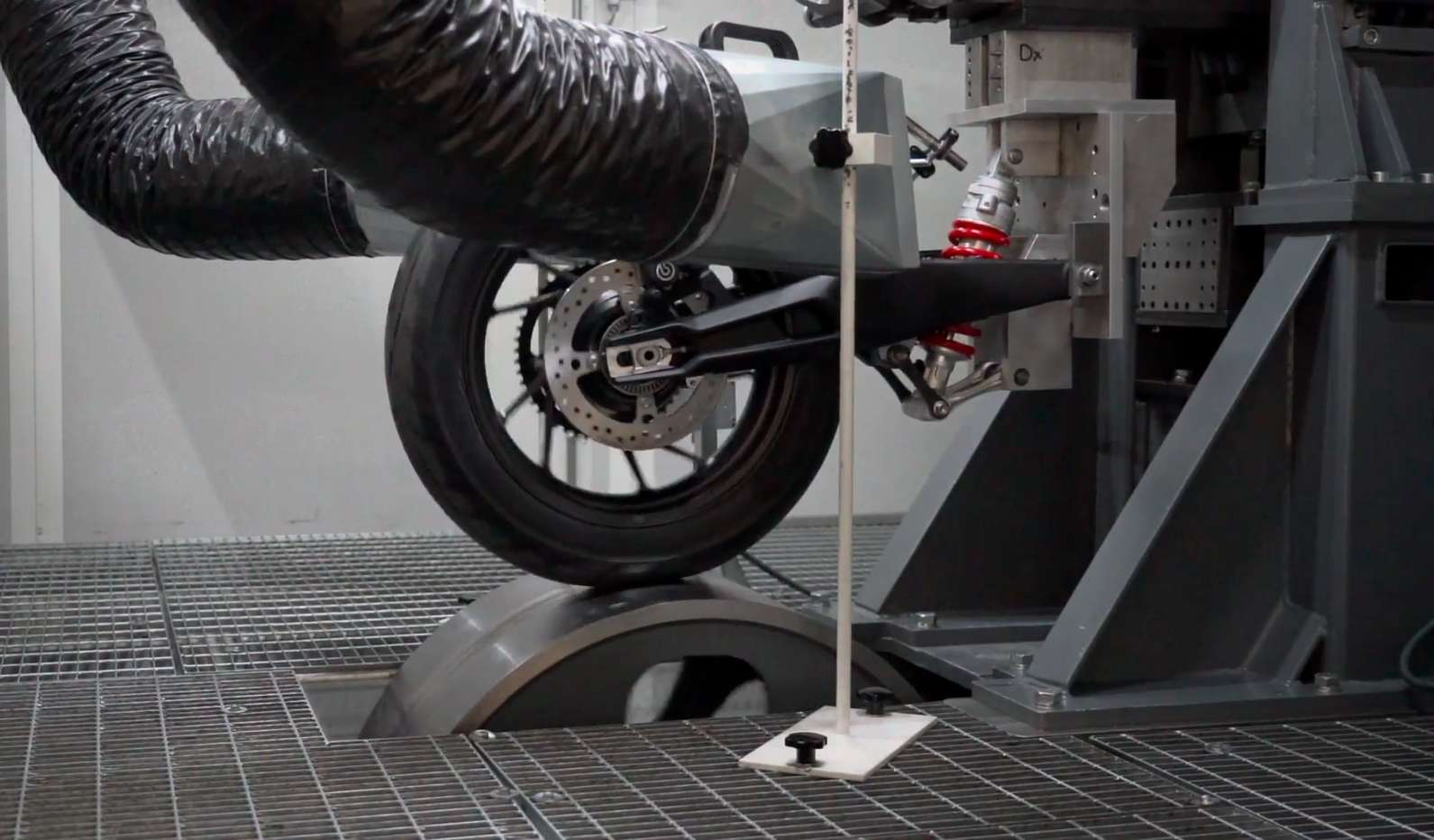 Motorcycle rear suspension dyno testing rig measuring shock performance in lab.