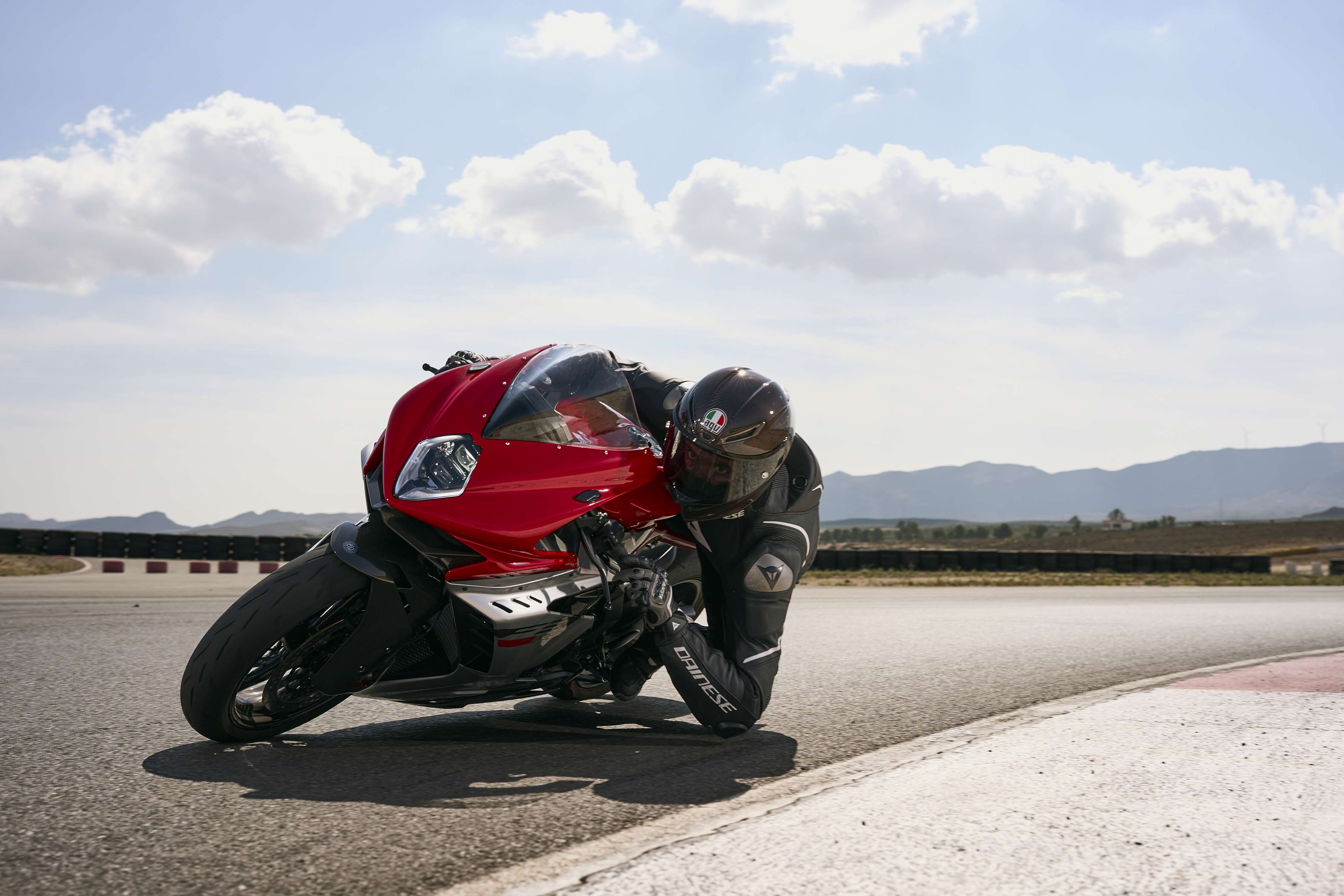 Red sport motorcycle leaning aggressively through a racetrack corner, showcasing high-performance suspension and precision track handling.
