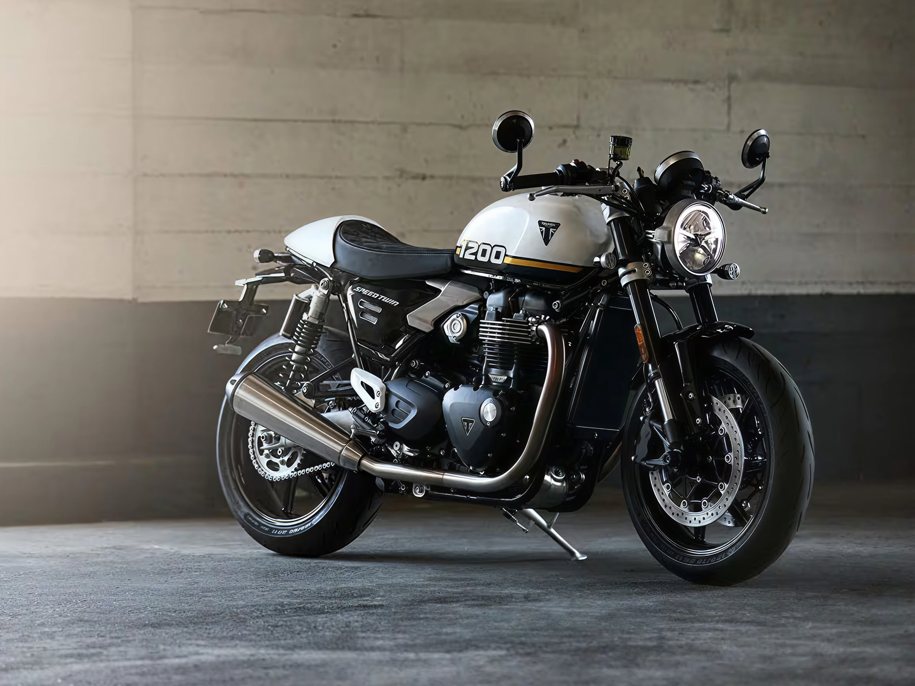 Triumph Speed Twin 1200 modern classic motorcycle in white and black finish parked indoors.